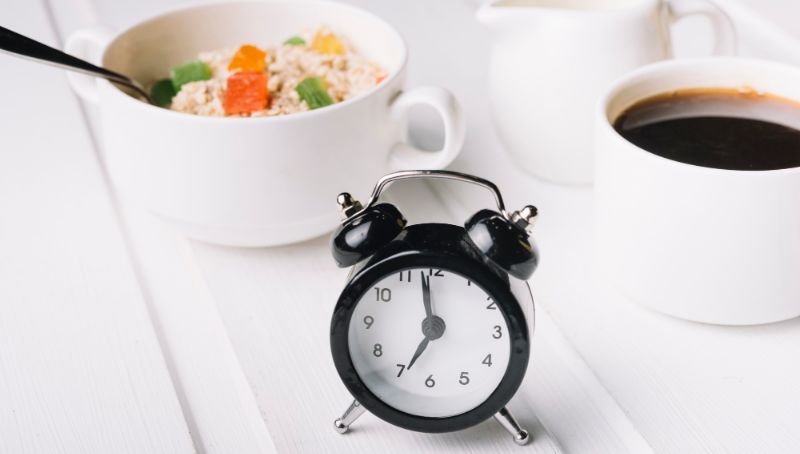photo alarm clock and oatmeal breakfast on white table